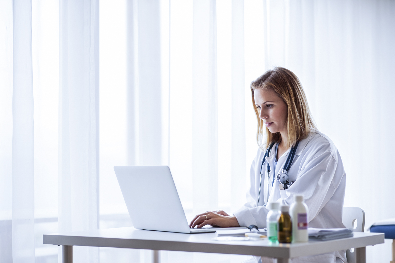 Female doctor with laptop working at the office desk.